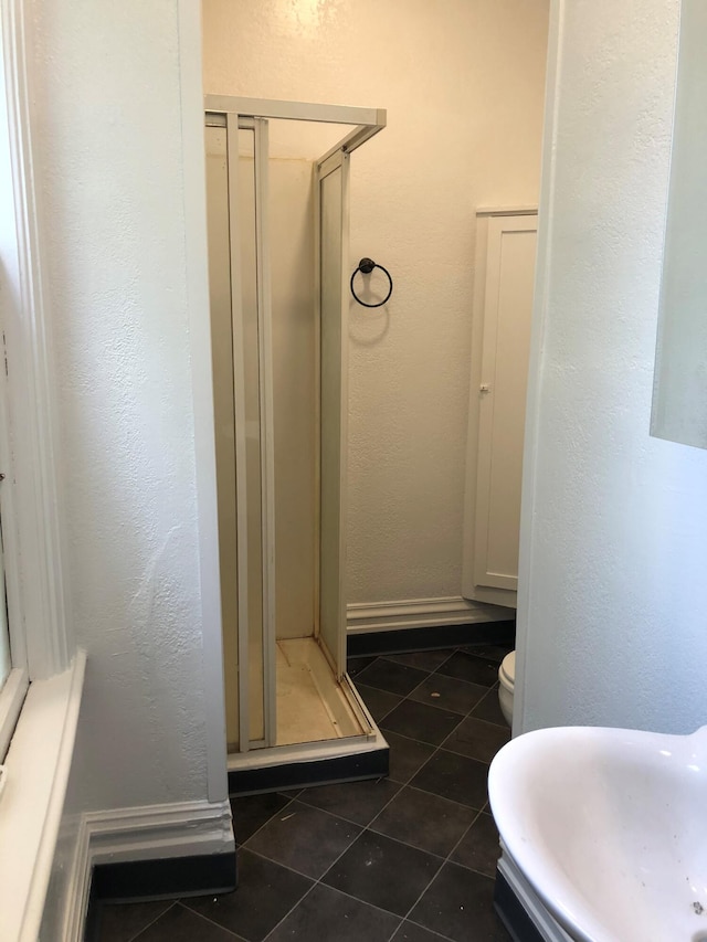 bathroom with tile patterned flooring, toilet, and a shower with door