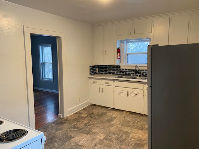 kitchen with white cabinets, a healthy amount of sunlight, sink, and stainless steel refrigerator