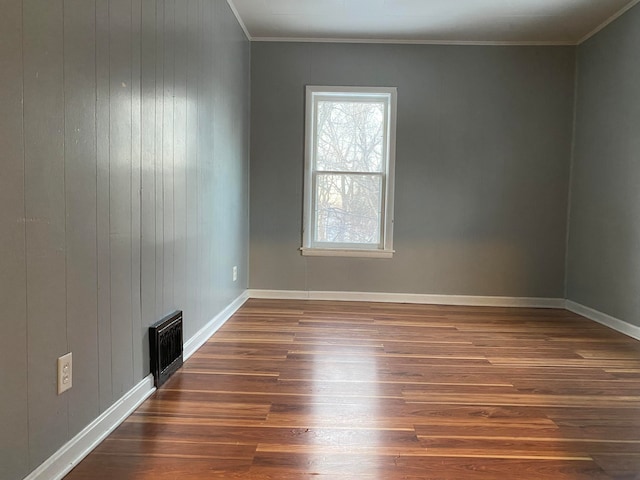 spare room featuring dark hardwood / wood-style flooring, ornamental molding, and wood walls