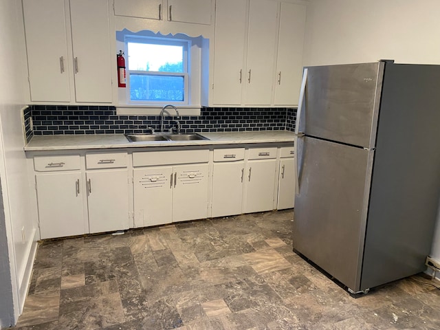 kitchen featuring white cabinets, stainless steel fridge, sink, and tasteful backsplash