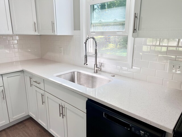 kitchen featuring dishwasher, light stone counters, white cabinetry, and sink