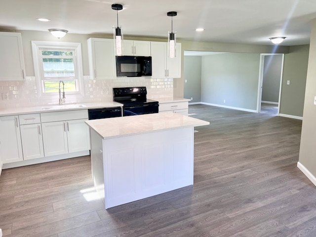 kitchen with sink, black appliances, light hardwood / wood-style floors, white cabinetry, and hanging light fixtures