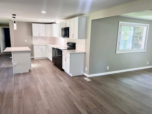 kitchen featuring a center island, dark wood-type flooring, black appliances, white cabinets, and decorative light fixtures