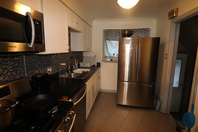 kitchen featuring white cabinetry, sink, backsplash, light tile patterned flooring, and appliances with stainless steel finishes