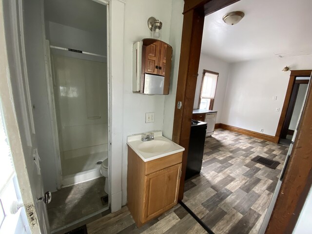 925 W Lovell St, Kalamazoo, MI 49007 - full bathroom featuring a stall shower, vanity, toilet, and wood finished floors