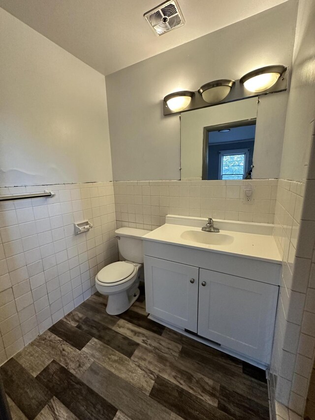 925 W Lovell St, Kalamazoo, MI 49007 - bathroom featuring tile walls, wood finished floors, toilet, vanity, and wainscoting