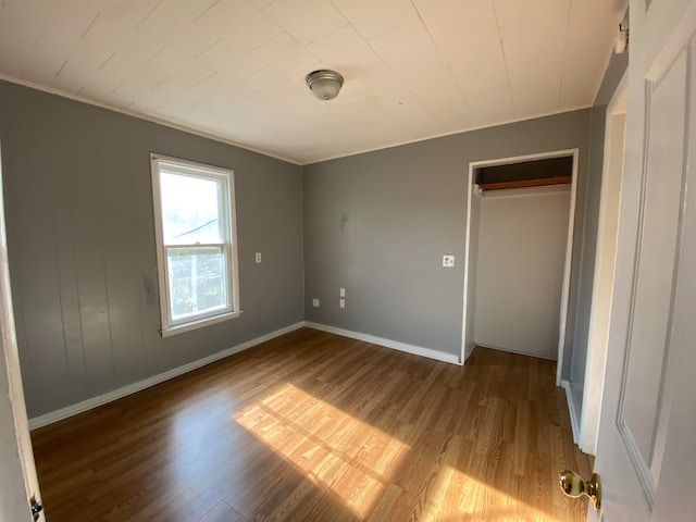 unfurnished bedroom with a closet, ornamental molding, and hardwood / wood-style flooring