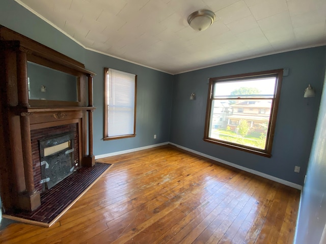 unfurnished living room with a tile fireplace, crown molding, and hardwood / wood-style floors