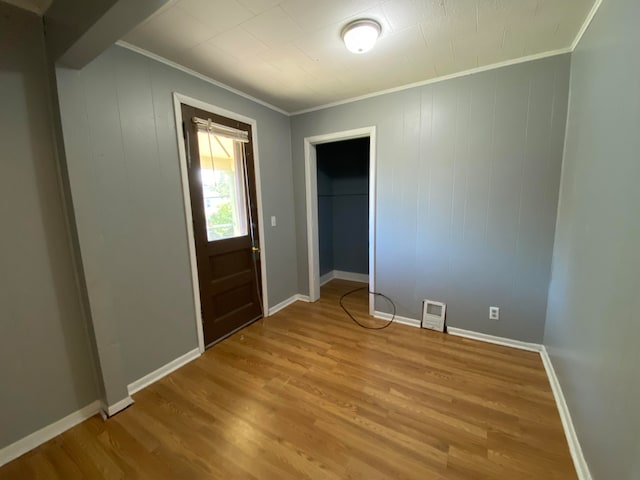 foyer featuring light hardwood / wood-style floors, crown molding, and wood walls