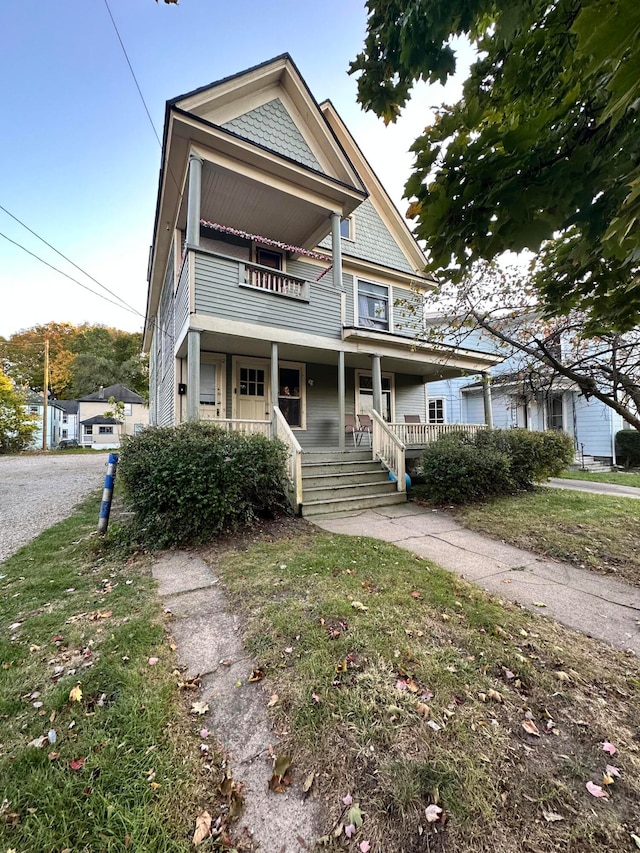 victorian house featuring covered porch and a front lawn