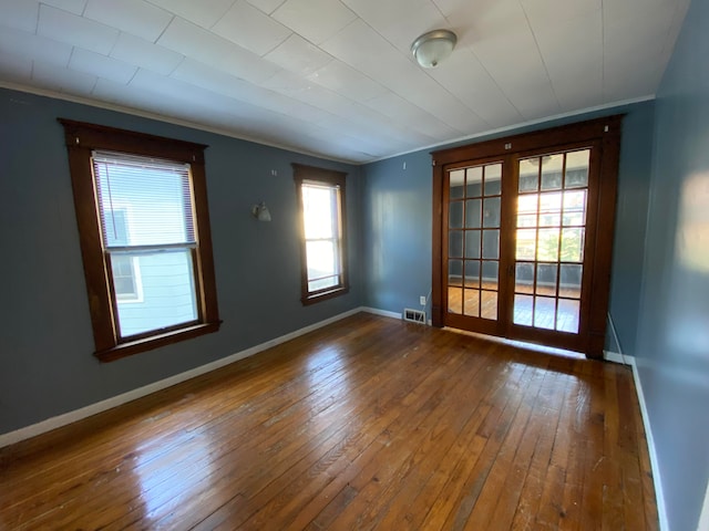 unfurnished room with ornamental molding, dark wood-type flooring, a wealth of natural light, and french doors