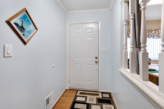 doorway featuring a textured ceiling, wood-type flooring, and crown molding