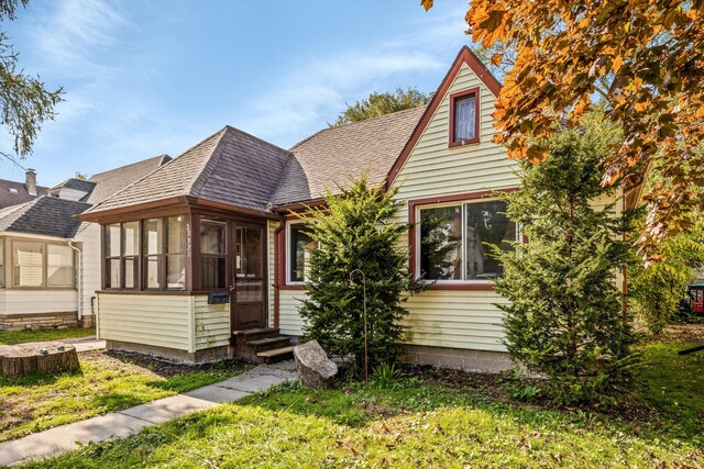 view of front facade featuring a sunroom and a front lawn