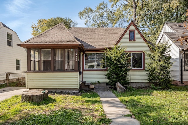 view of front of house with a sunroom and a front lawn