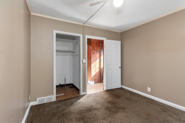 unfurnished bedroom featuring dark colored carpet, crown molding, a textured ceiling, a closet, and ceiling fan