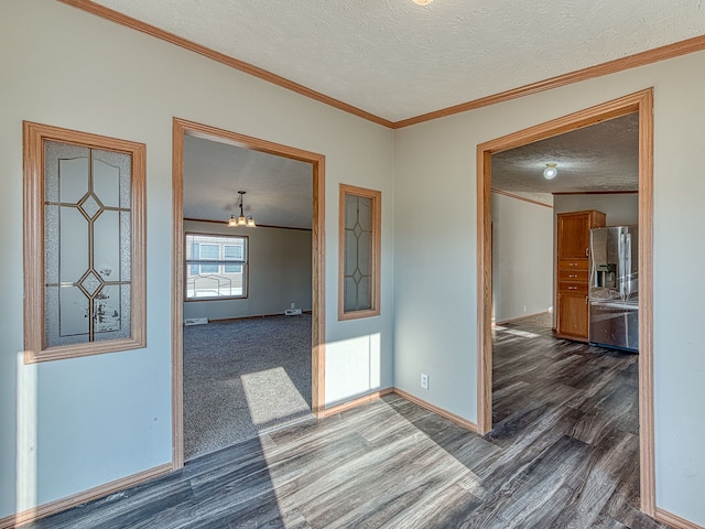 spare room with dark hardwood / wood-style floors, crown molding, a textured ceiling, and an inviting chandelier