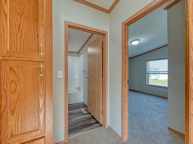 corridor featuring vaulted ceiling, carpet, a textured ceiling, and ornamental molding