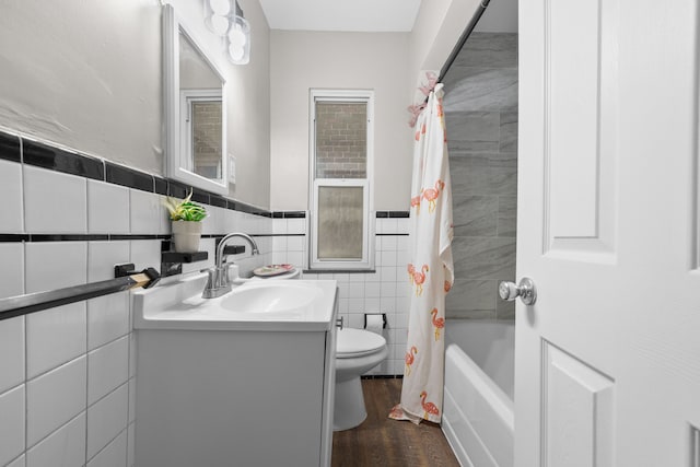 full bathroom featuring hardwood / wood-style flooring, shower / bath combo with shower curtain, tile walls, toilet, and vanity