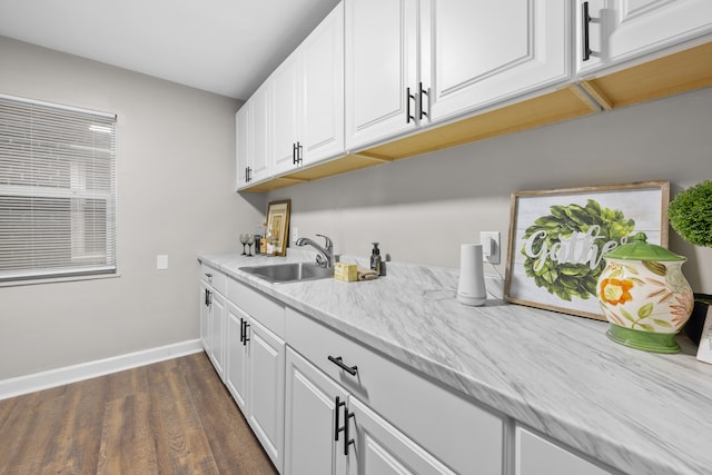 kitchen with sink, white cabinetry, dark wood-type flooring, and light stone counters