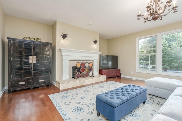 living room featuring a tile fireplace, hardwood / wood-style flooring, and an inviting chandelier