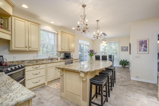 kitchen with pendant lighting, a center island, cream cabinets, a kitchen breakfast bar, and light stone counters