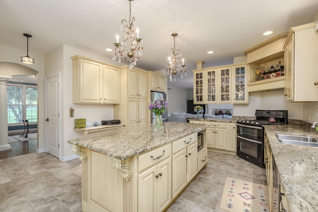 kitchen with cream cabinets, hanging light fixtures, and black range oven