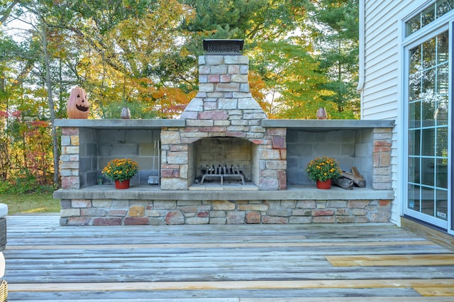 wooden deck with an outdoor stone fireplace