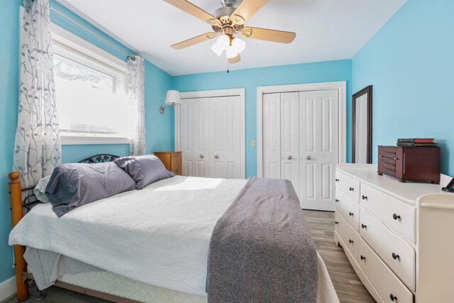 bedroom featuring dark hardwood / wood-style floors, ceiling fan, and multiple closets