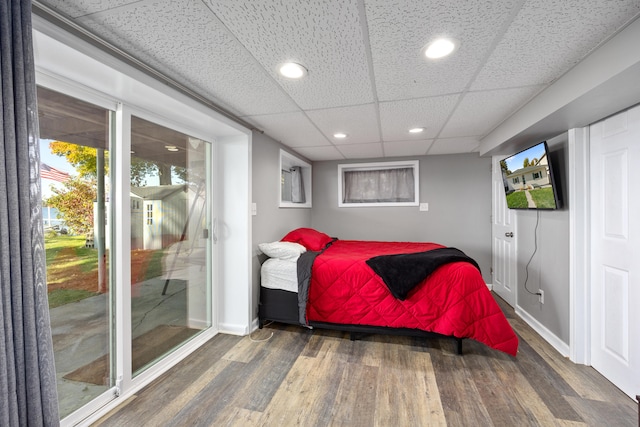 bedroom featuring dark hardwood / wood-style flooring, access to outside, and a paneled ceiling