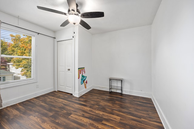 unfurnished bedroom with ceiling fan, dark wood-type flooring, and a closet