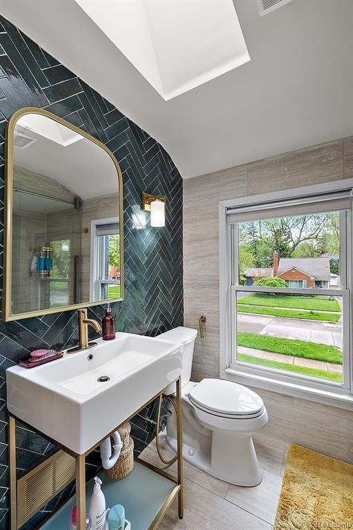 bathroom featuring vaulted ceiling, hardwood / wood-style floors, tile walls, and toilet