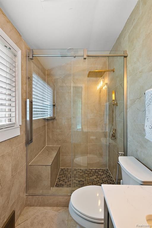 bathroom featuring tile patterned flooring, vanity, toilet, and walk in shower