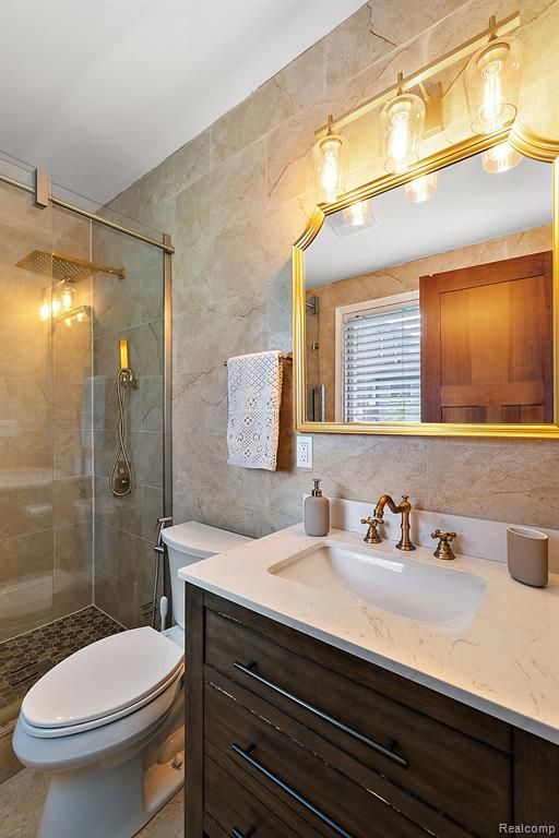 bathroom featuring decorative backsplash, walk in shower, vanity, tile walls, and toilet