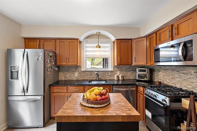 kitchen with wooden counters, appliances with stainless steel finishes, backsplash, sink, and a center island