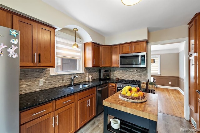 kitchen with wooden counters, appliances with stainless steel finishes, backsplash, sink, and light hardwood / wood-style flooring