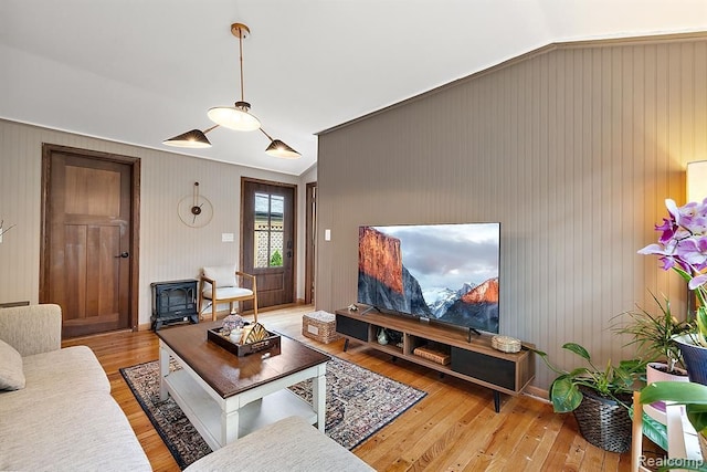 living room with a wood stove, hardwood / wood-style floors, and lofted ceiling