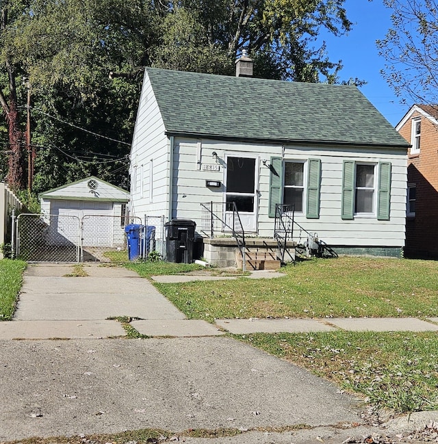 bungalow featuring a garage, an outdoor structure, and a front lawn