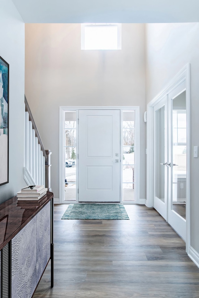 entryway featuring dark wood-type flooring, a high ceiling, baseboards, stairs, and french doors