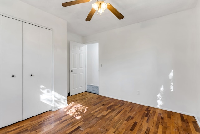 unfurnished bedroom featuring hardwood / wood-style floors, ceiling fan, and a closet