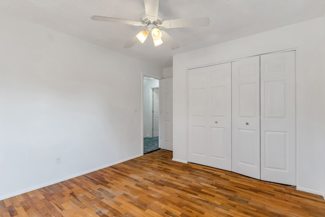 unfurnished bedroom featuring hardwood / wood-style flooring, ceiling fan, and a closet