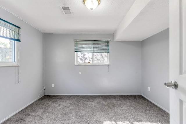 spare room with a textured ceiling and light carpet