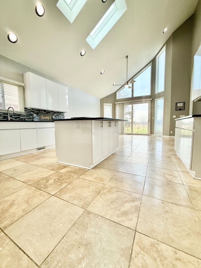 kitchen with sink, a center island, high vaulted ceiling, ceiling fan, and white cabinets