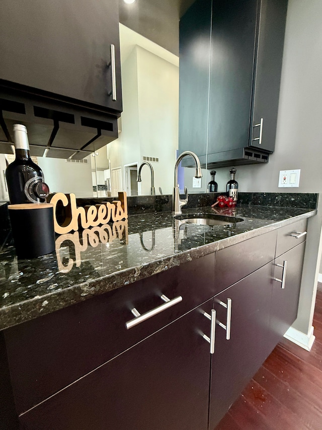 kitchen featuring sink, dark wood-type flooring, and dark stone counters