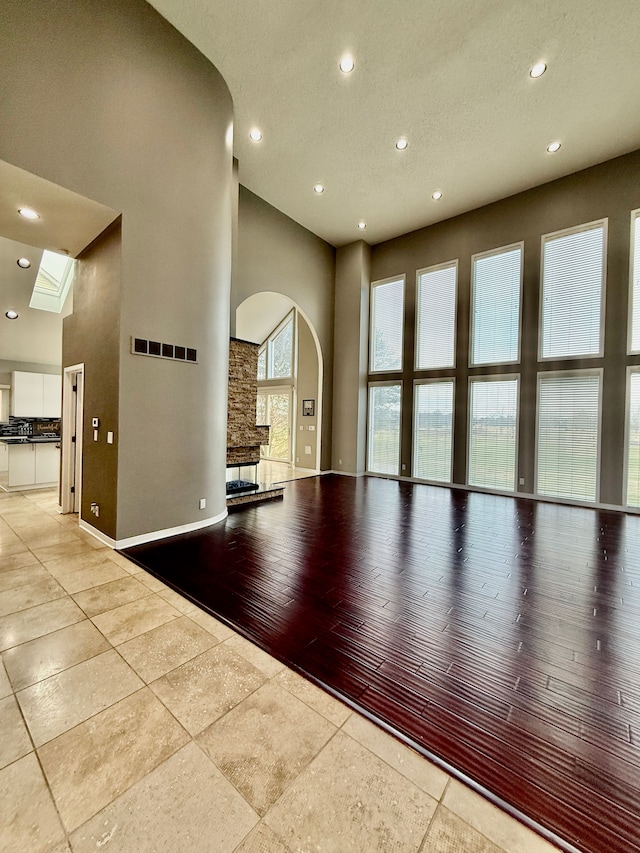 spare room with light tile patterned flooring, a towering ceiling, and a textured ceiling