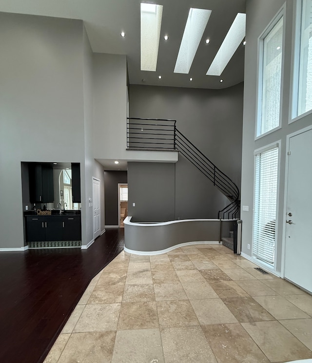 foyer featuring a high ceiling, hardwood / wood-style flooring, sink, and a skylight