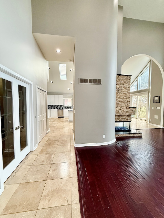 corridor featuring a high ceiling, light wood-type flooring, and french doors