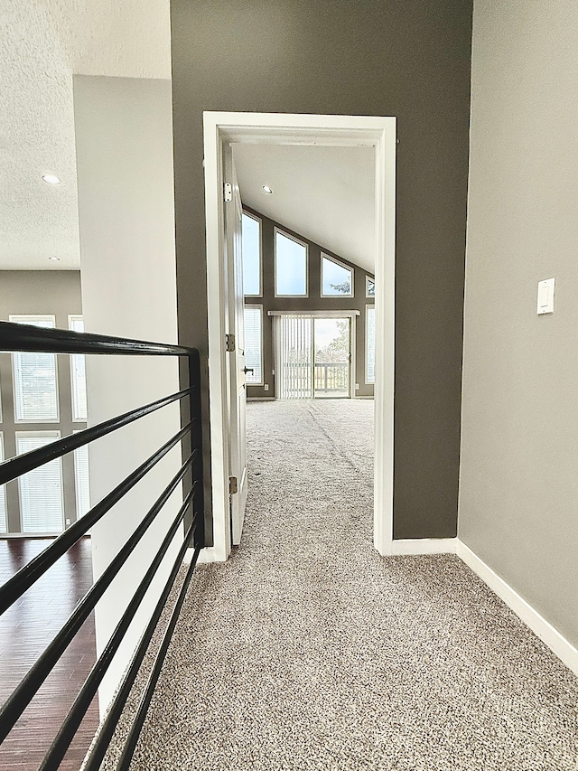 hall featuring lofted ceiling, a textured ceiling, and carpet flooring