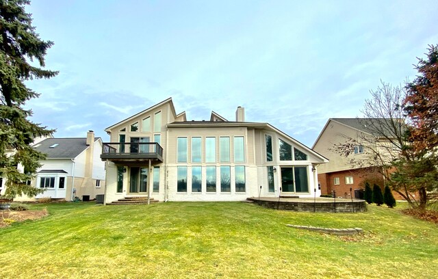 rear view of house with a balcony and a yard