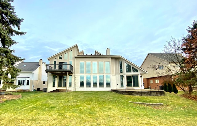 back of house featuring a balcony and a lawn