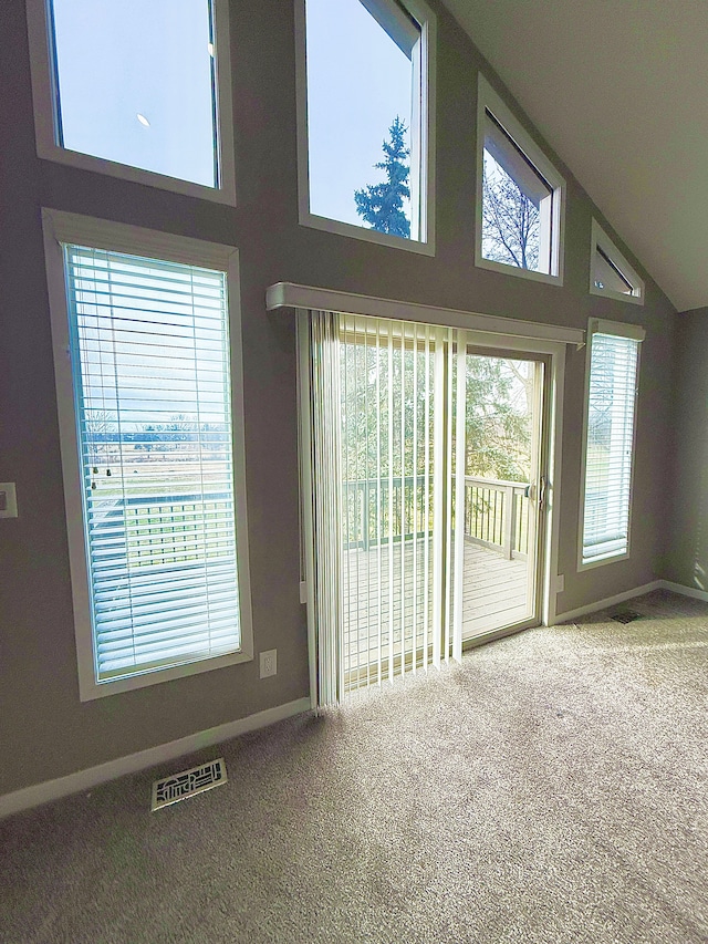 unfurnished living room with high vaulted ceiling and carpet flooring